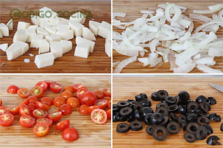 Queso fresco, tomates cherry, aceitunas negras y cebolla cortados para hacer una ensalada